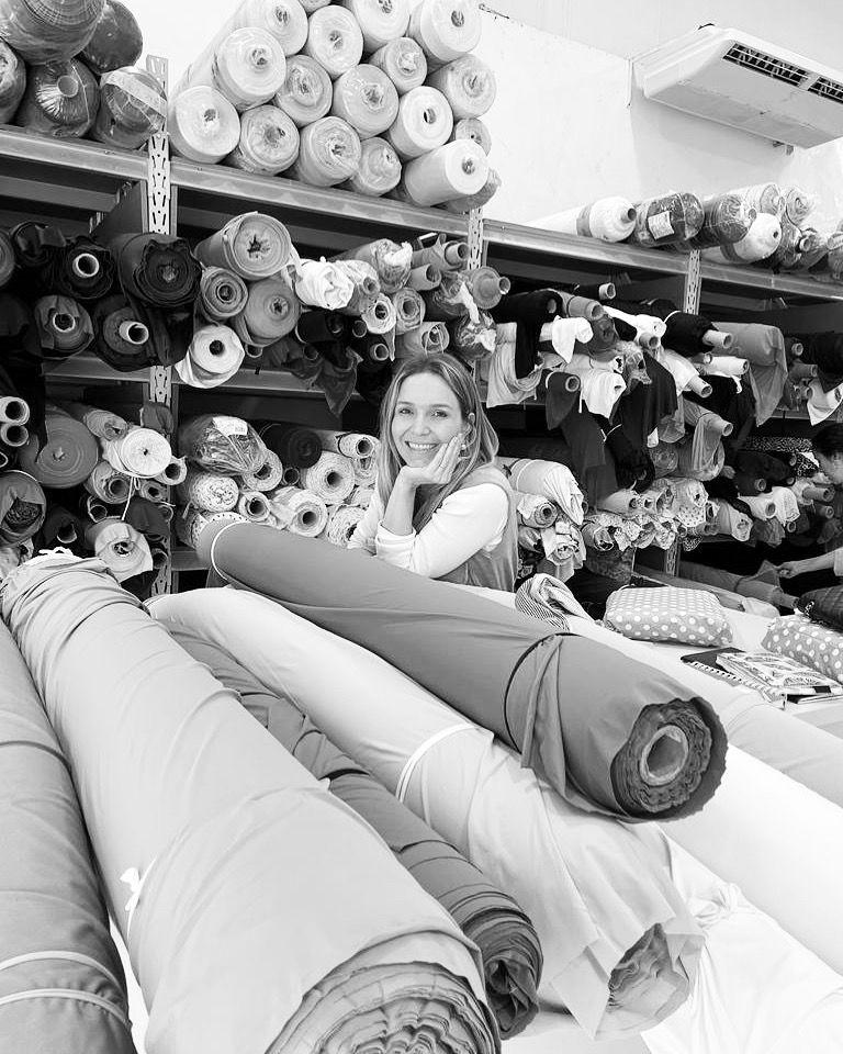 Helen Marini entre rolos de tecido durante a escolha de materiais da Aurora Bebê.